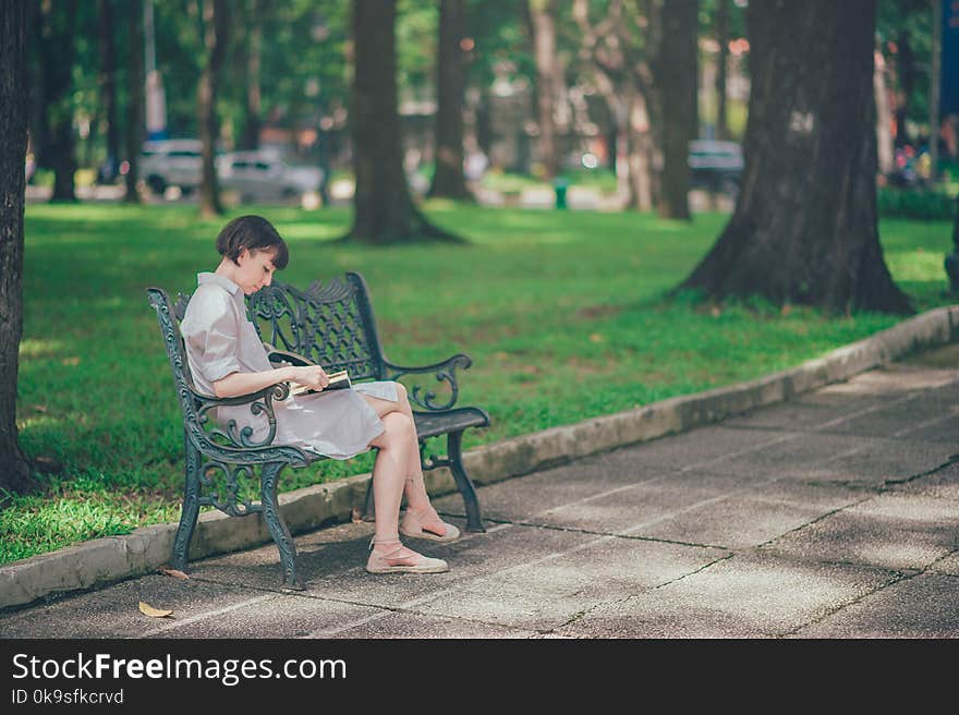 Photo of Woman Wearing Gray Dress Sitting on Bench