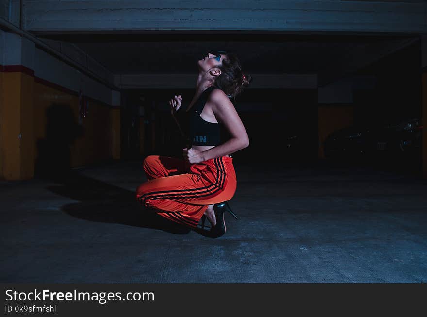 Woman in Black Crop Top Sitting on Concrete Floor