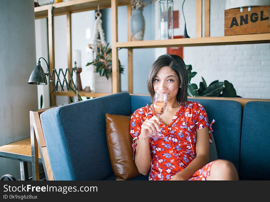 Woman Wearing Red, Purple, and Pink Floral V-neck Cap-sleeved Dress Drinking Through Clear Wine Glass