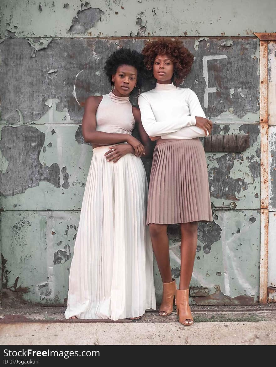 Two Women Standing Beside Wall at Daytime