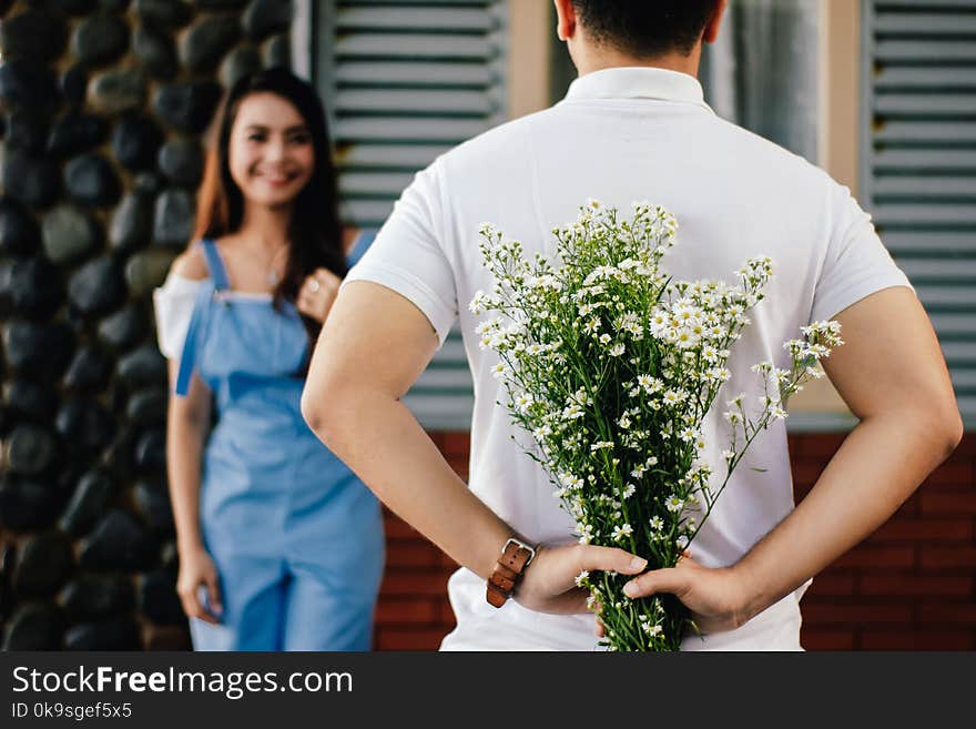 Man Holding Baby&#x27;s-breath Flower in Front of Woman Standing Near Marble Wall