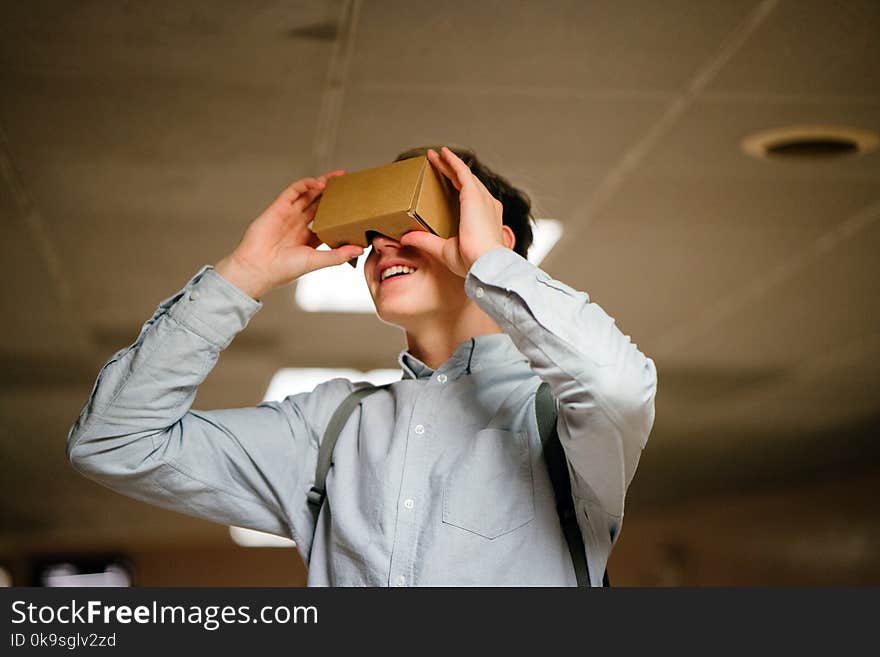 Man in Grey Dress Shirt Using Brown Cardboard Vr Glasses