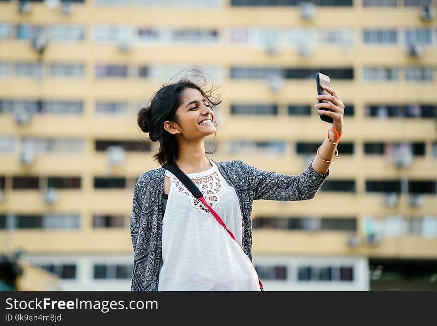 Smiling Woman Holding Black Smartphone