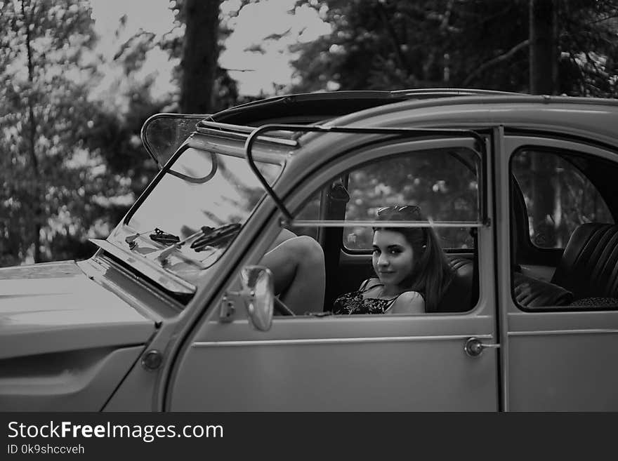 Grayscale Photo Of Woman Inside Classic Car