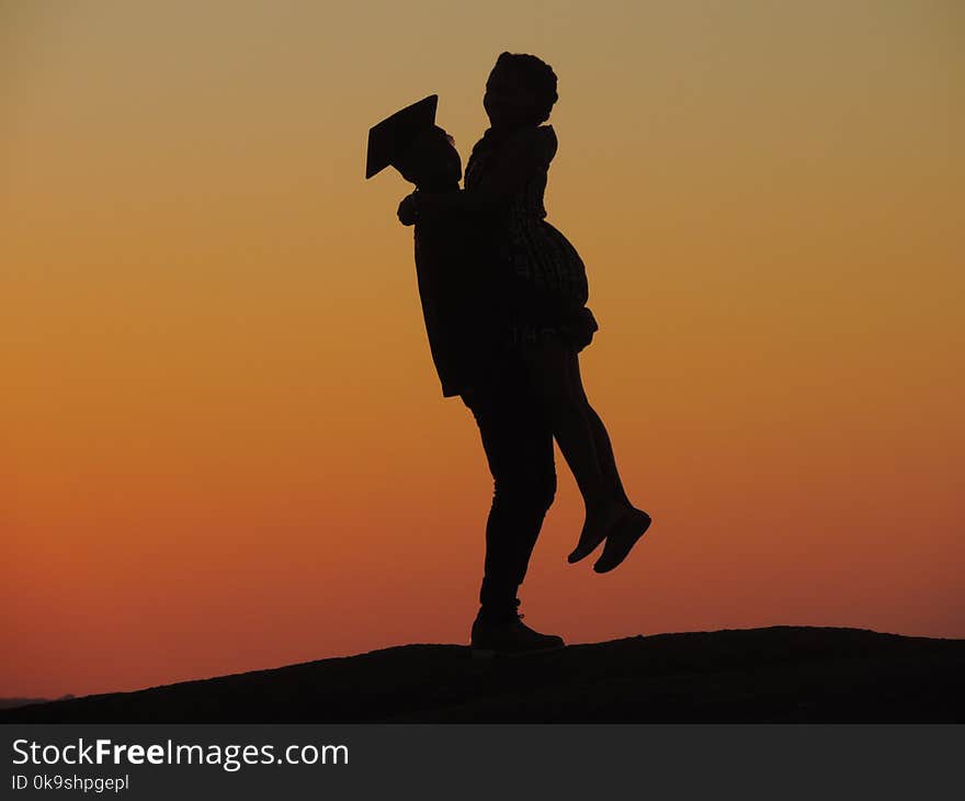 Silhouette Photo Of Man Carrying Woman Under Orange Sky