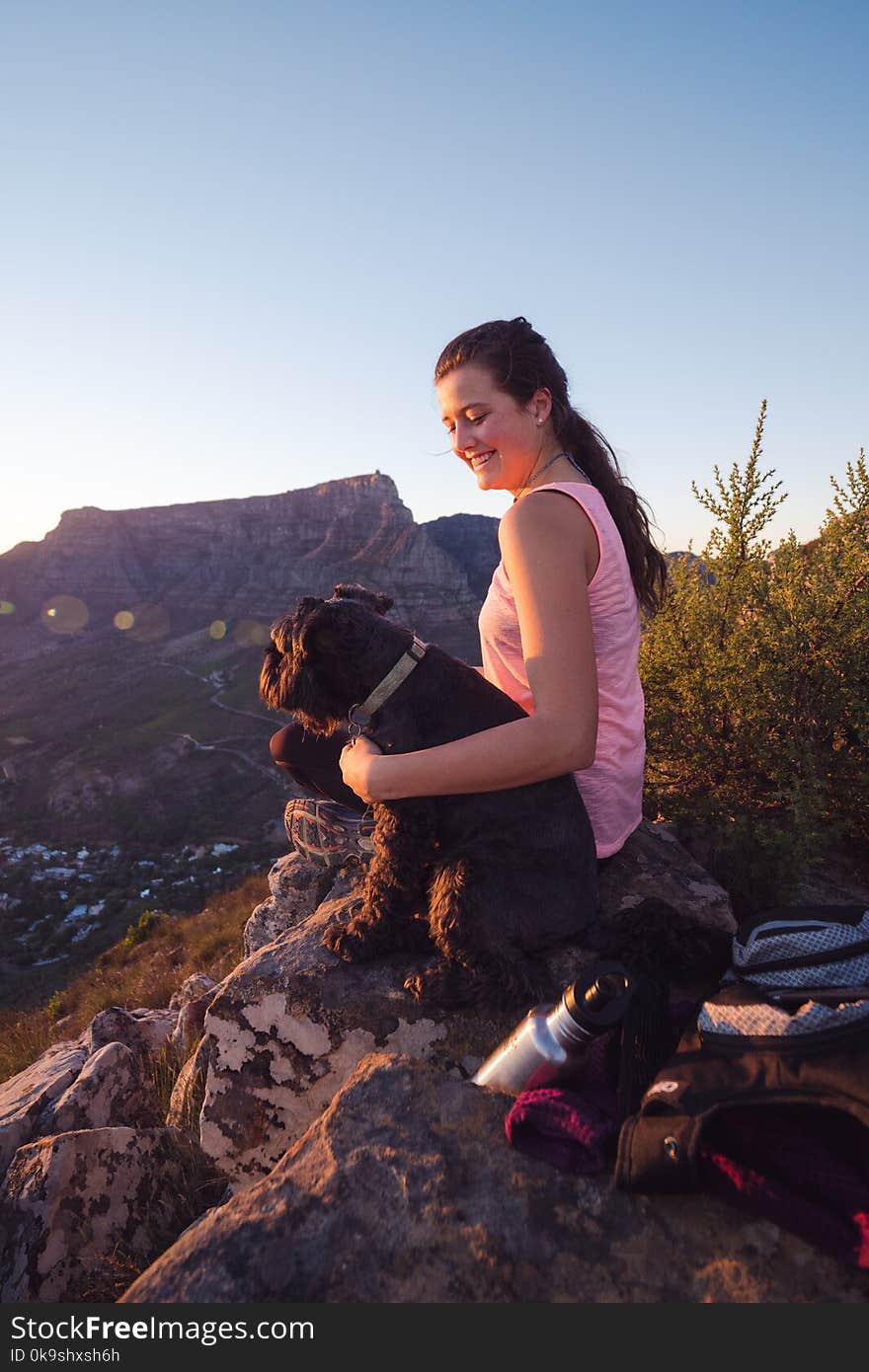 Woman Wearing Pink Tank Top Sitting on Rock Beside Dog