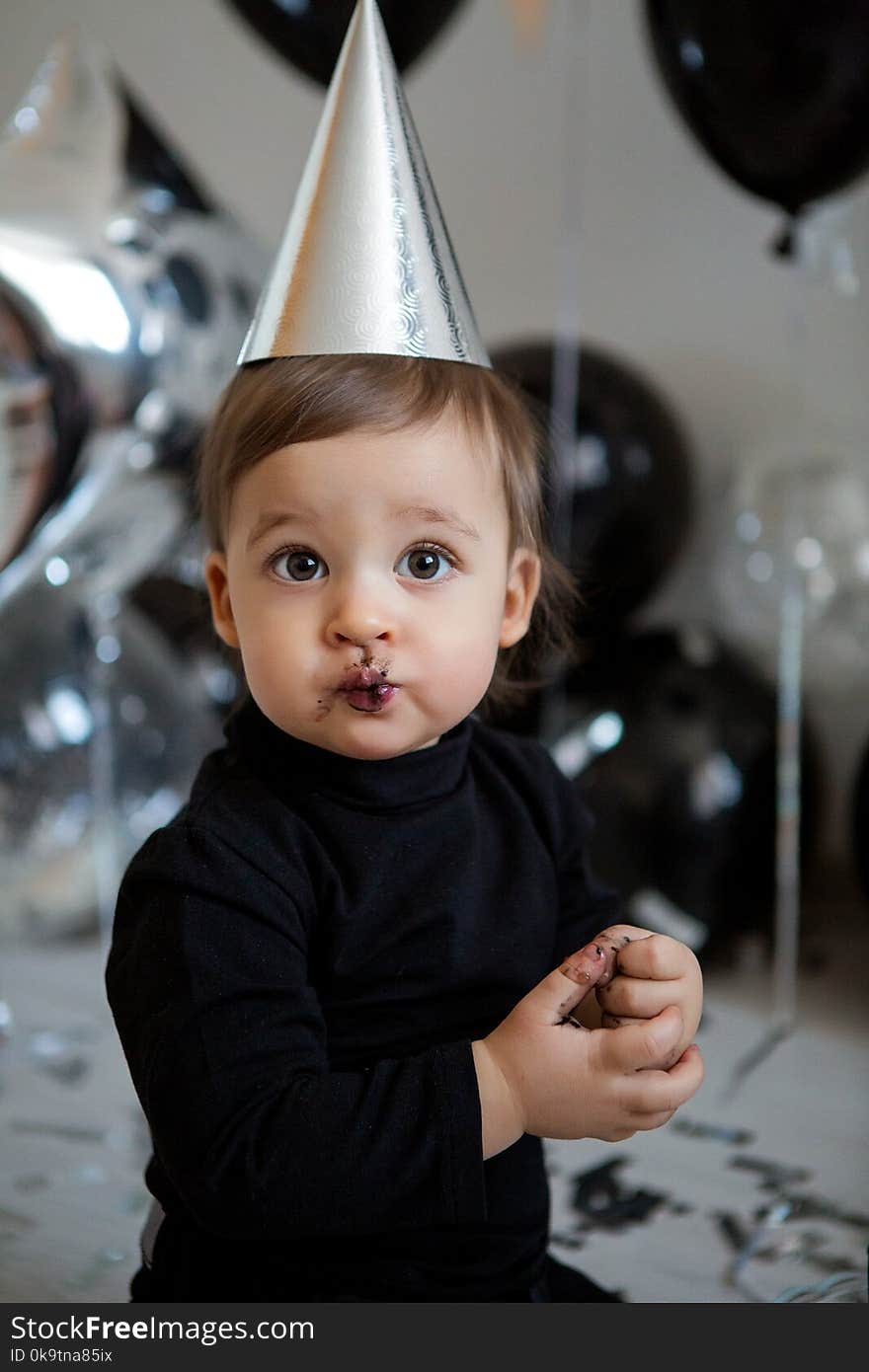 Boy stands next to a festive black cake