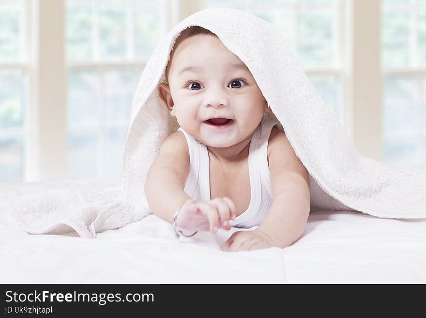 Closeup of joyful male toddler crawling on the bedroom under a towel. Closeup of joyful male toddler crawling on the bedroom under a towel