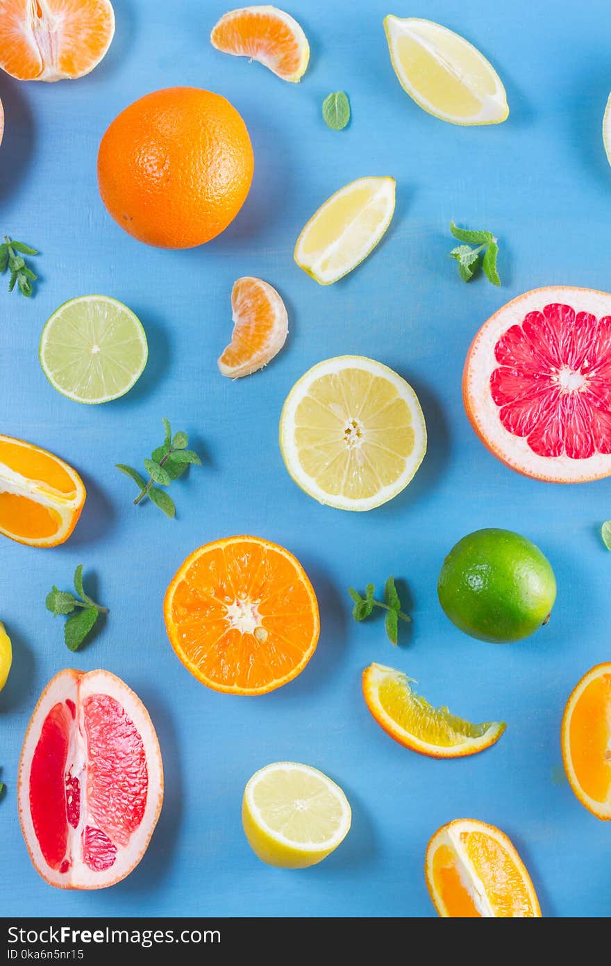 Natural citrus food pattern on blue background - assorted citrus fruits with mint leaves. Natural citrus food pattern on blue background - assorted citrus fruits with mint leaves