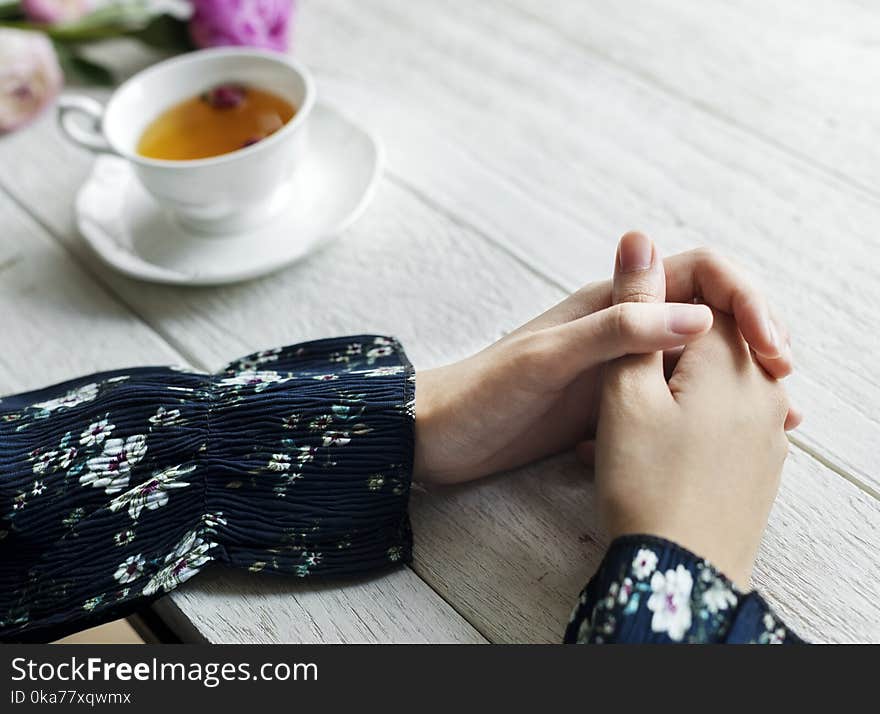 Person in Blue and White Sleeved Shirt Near on White Ceramic Teacup