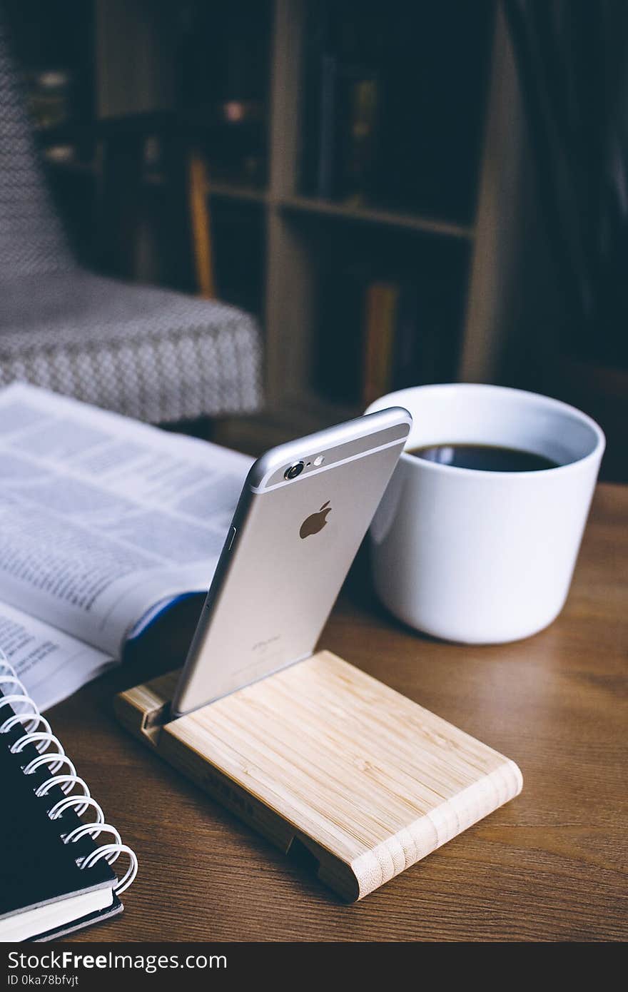 Silver Iphone on Brown Wooden Rack on Top of Table