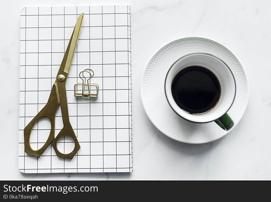 Cup of Coffee Beside Book and Scissors