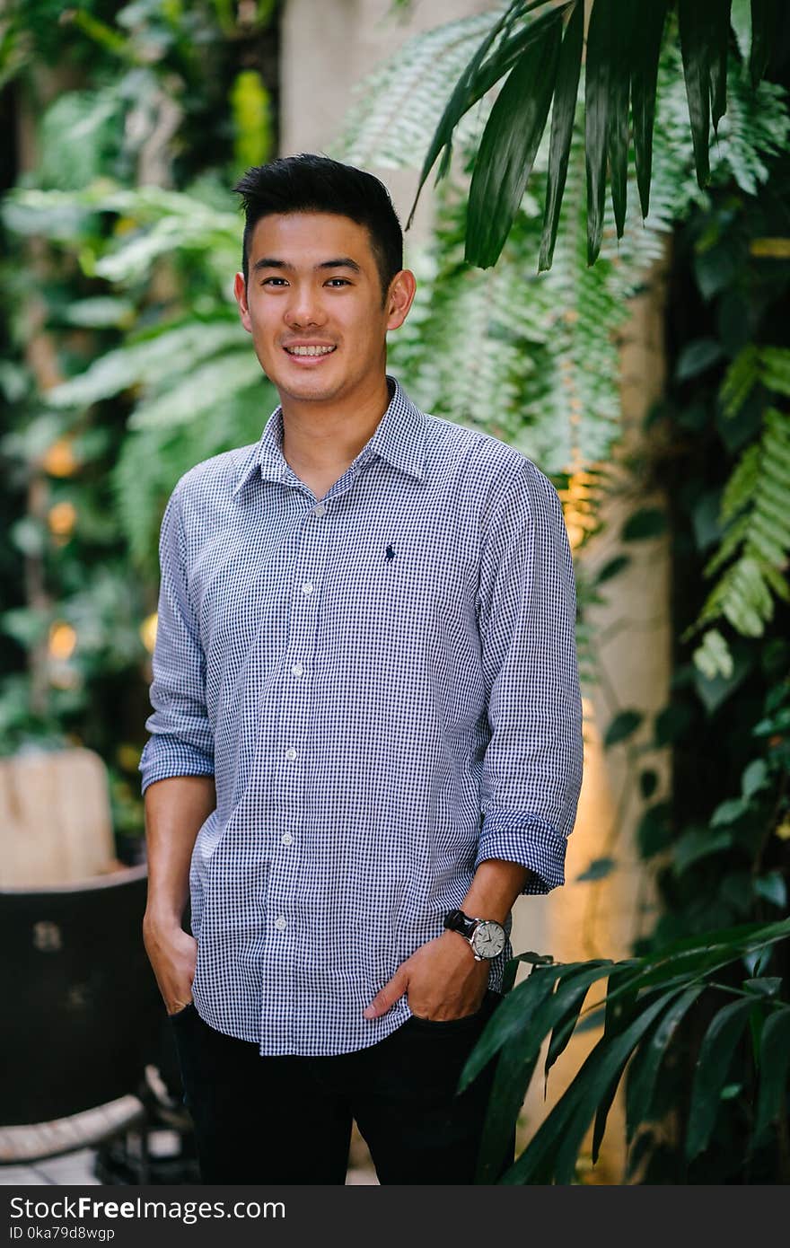 Man Wearing Blue Dress Shirt Standing Beside Green Plant