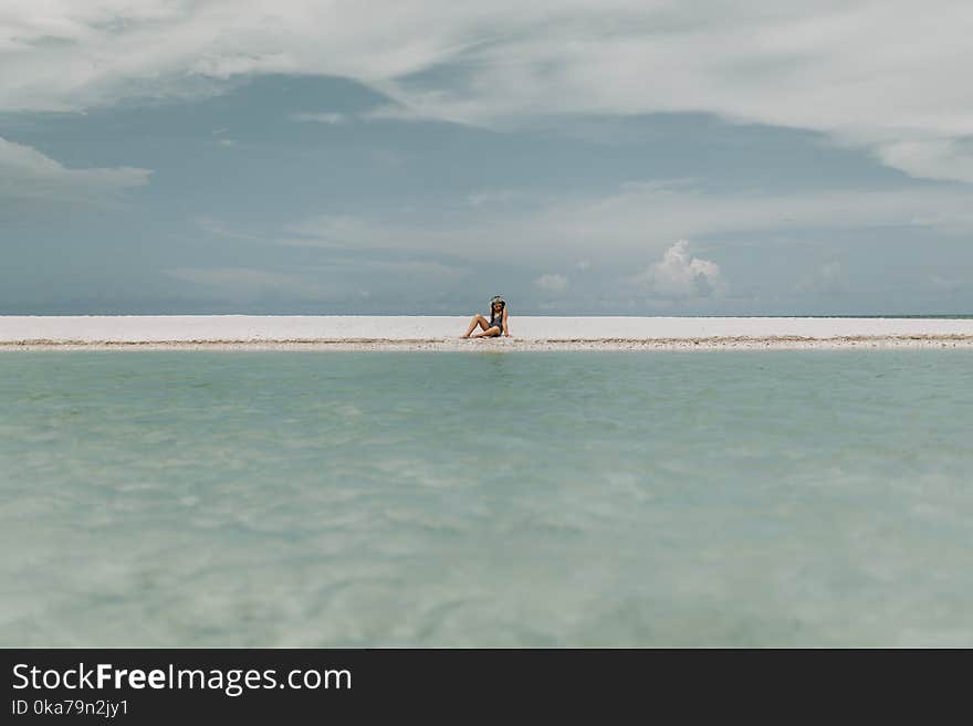 Person Sitting On White Sand