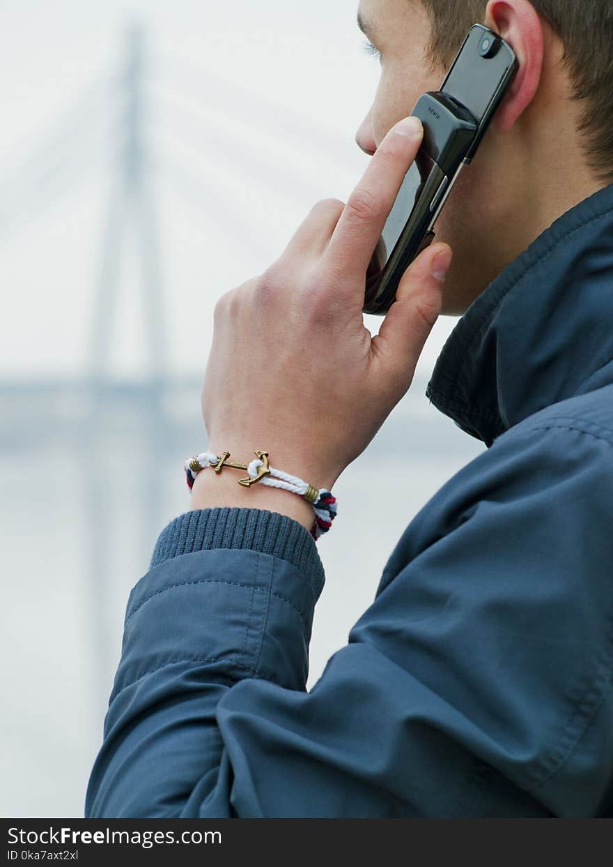 Man Wearing Blue Jacket Using His Mobile Phone