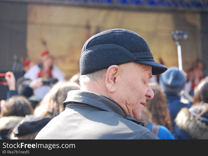 Man Wearing Cap And Grey Coat Surrounded With People