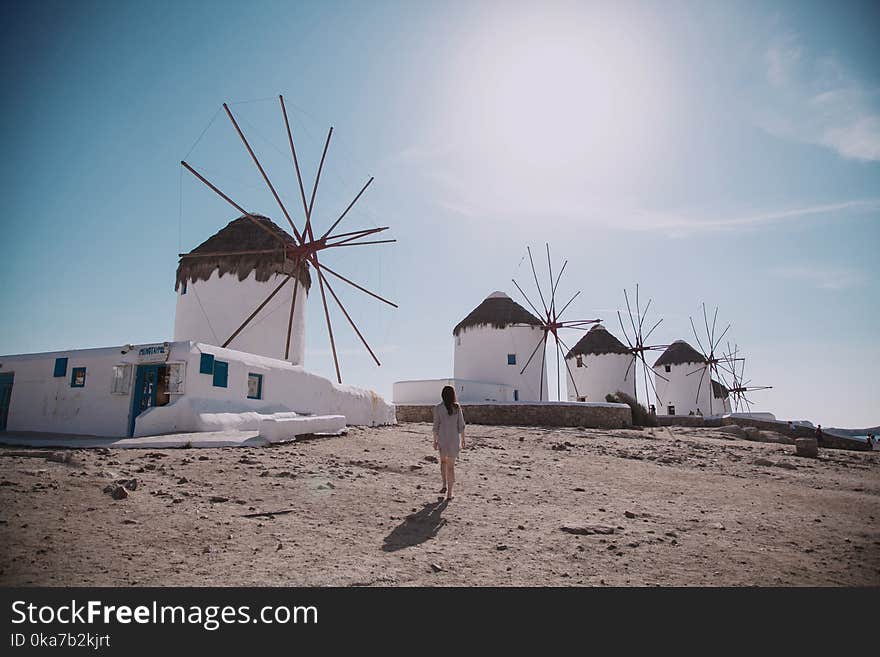 Woman Wearing Grey Dress Walking In Front Of Windmill Under Blue Sky