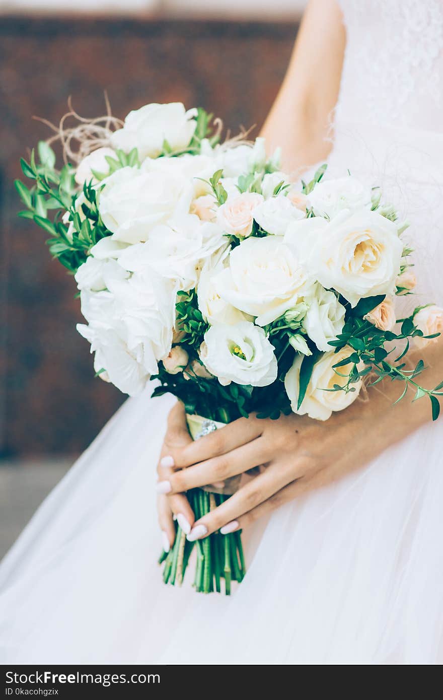 Bride in long sleeve wedding dress holds soft and tender bridal bouquet of roses. Bride in long sleeve wedding dress holds soft and tender bridal bouquet of roses