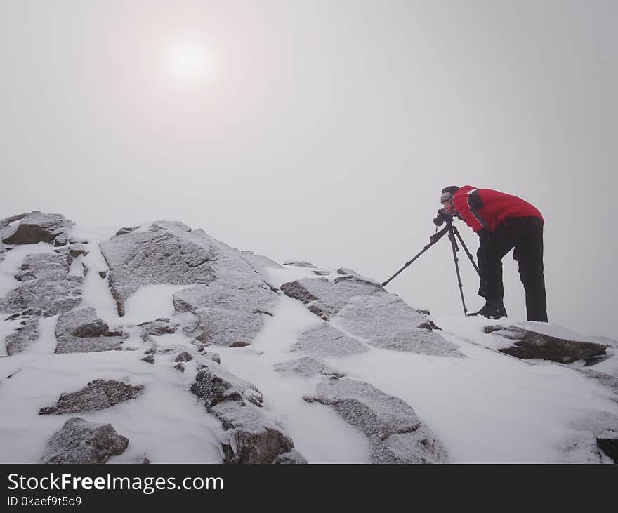 Tall hiker in black on peak of the world . Heavy orange mist bellow in valley.