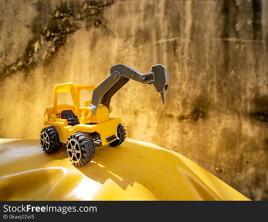 Jackhammer truck toy on yellow ground with grunge cement wall background