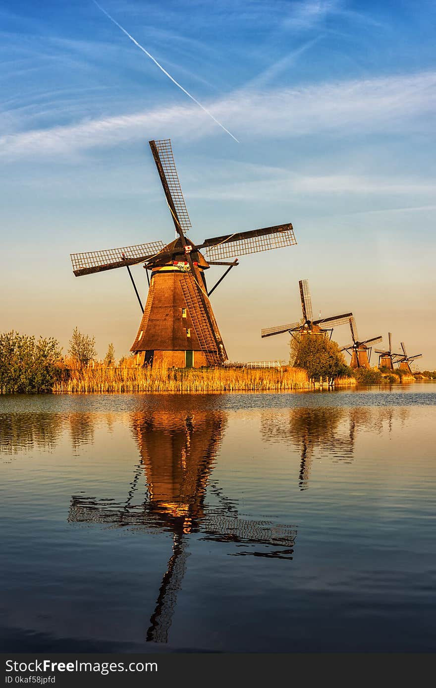 Mills in Netherland, Kinderdijk - scenic sunset landscape with windmills, blue sky and reflection in the water at soft light. Vertical image, nature background. Mills in Netherland, Kinderdijk - scenic sunset landscape with windmills, blue sky and reflection in the water at soft light. Vertical image, nature background