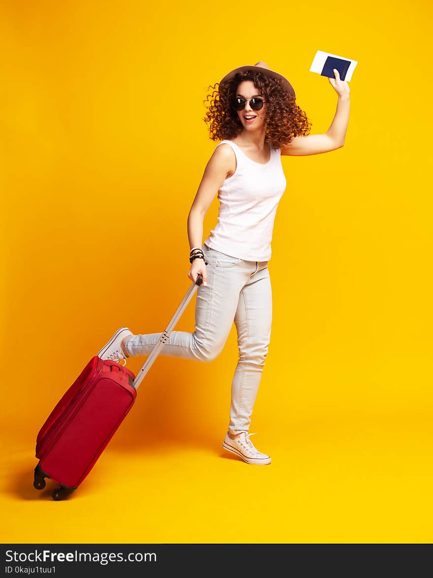 Woman traveler with suitcase on color background.