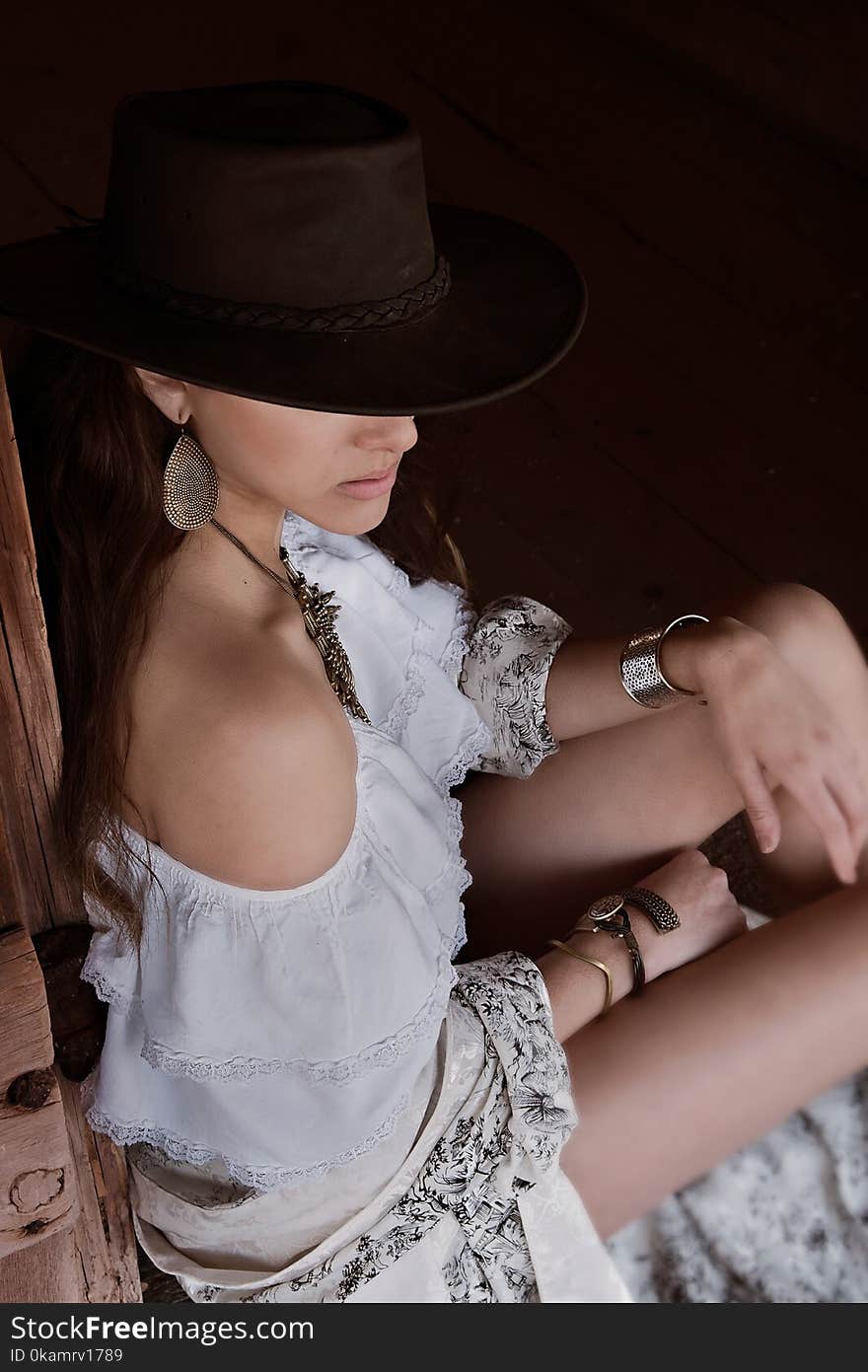 Photo of Woman in White Off-shoulder Top and Brown Cowboy Hat Sitting