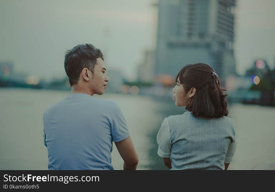 Man and Woman Facing Body of Water and Building