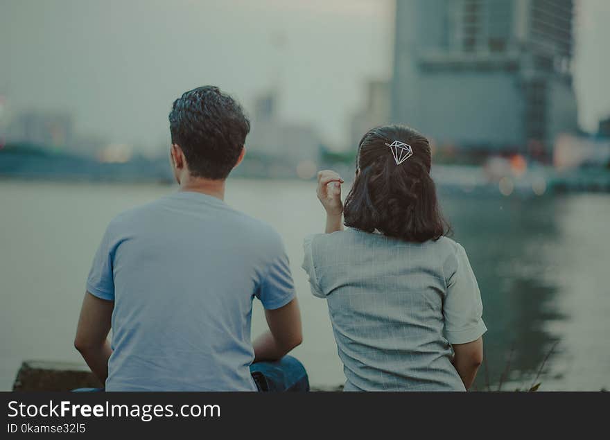 Man and Woman Wearing Shirt Facing Body of Water