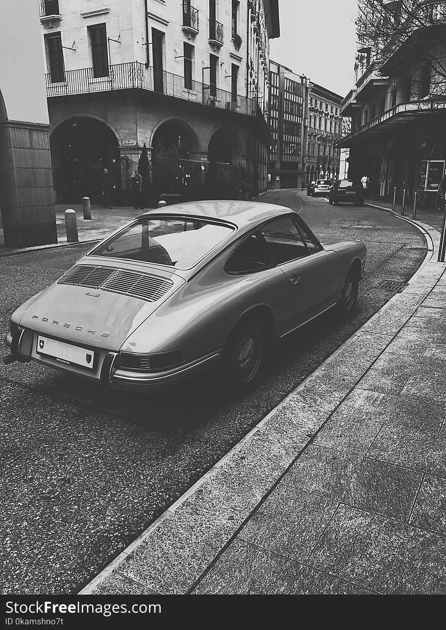 Grayscale Photo of Vintage Vehicle on Road Near Building