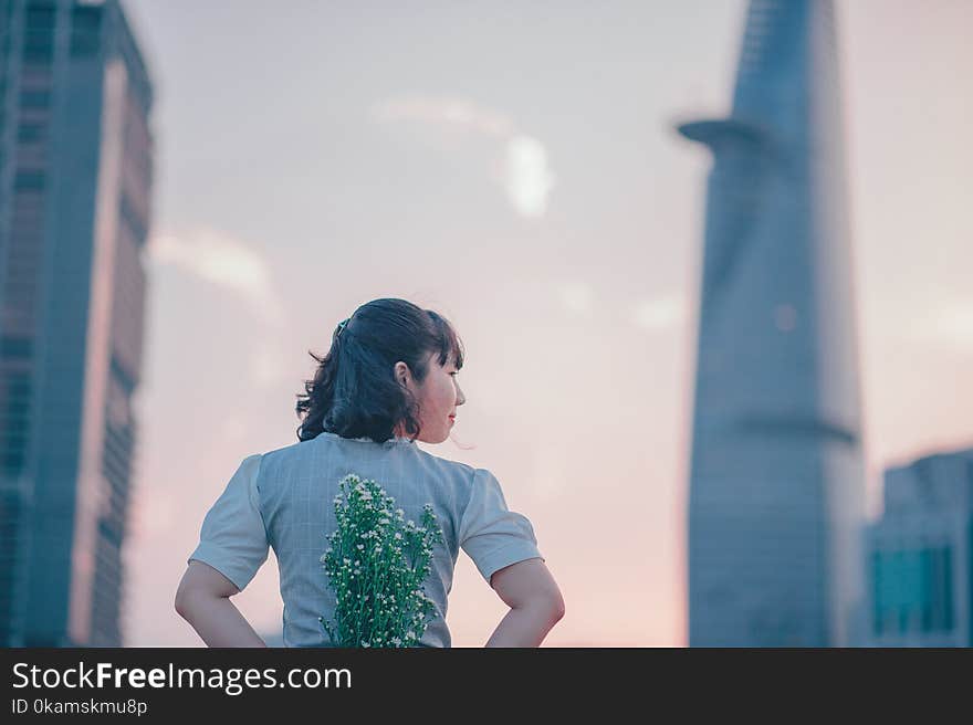 photo of Woman in Gray Top Holding Flowers on Her Back