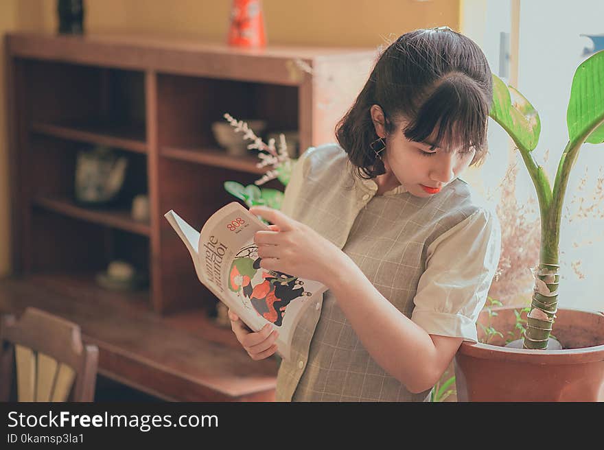 Woman in Grey Button-up Short-sleeved Top Holding Book