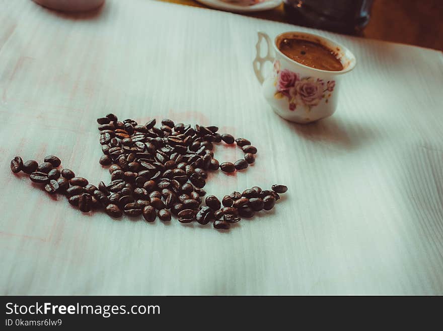 Brown Coffee Beans Beside Ceramic Mug on Table