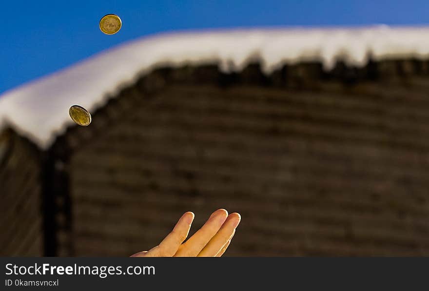 Shallow Focus Photography of Person Catching Two Gold-colored Coins