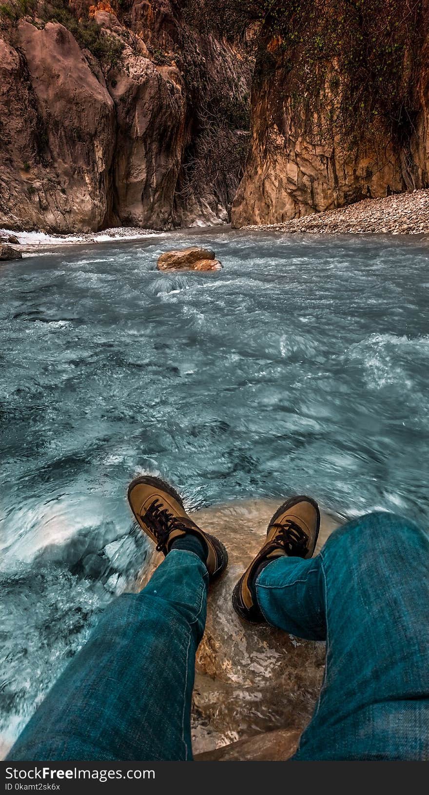 Person in Blue Jeans and Brown Sneaker Near Body of Water