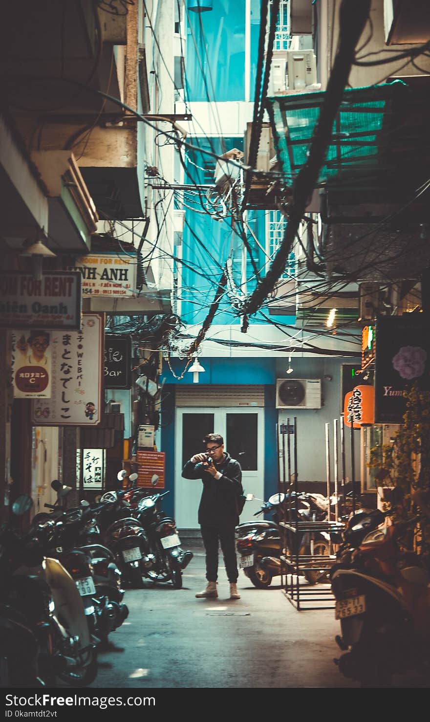 Man Standing on Concrete Road With Parked Motorcycles While Holding Dslr Camera