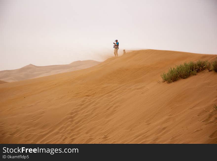 Man Standing on Brown Sand Under Gray Sky