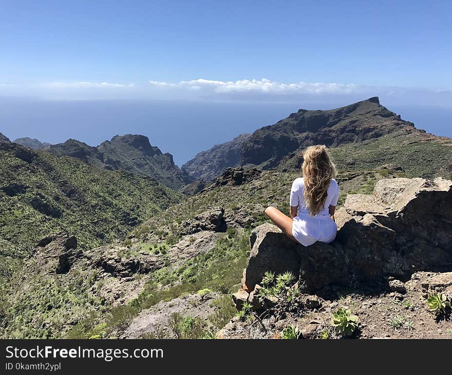 Woman in White Top Sitting on Rock