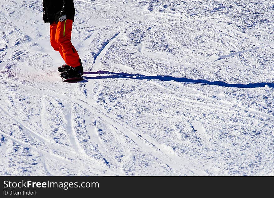 Photo of Person Wearing Black Top and Orange Pants Riding Snowboard