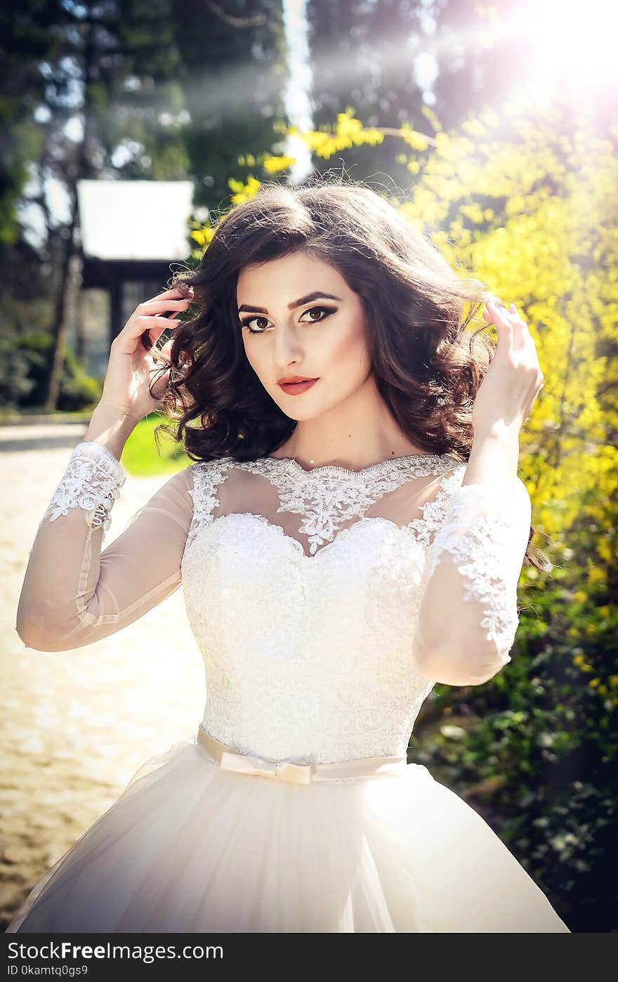 Photo of Woman in White Wedding Dress Holding Her Hair