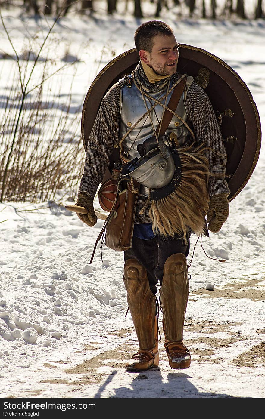 Man Wearing Armor and Walking in Snowy Field