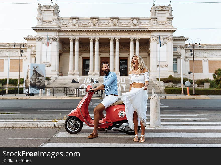 Man Riding on the Motorcycle Beside Woman Standing on the Road