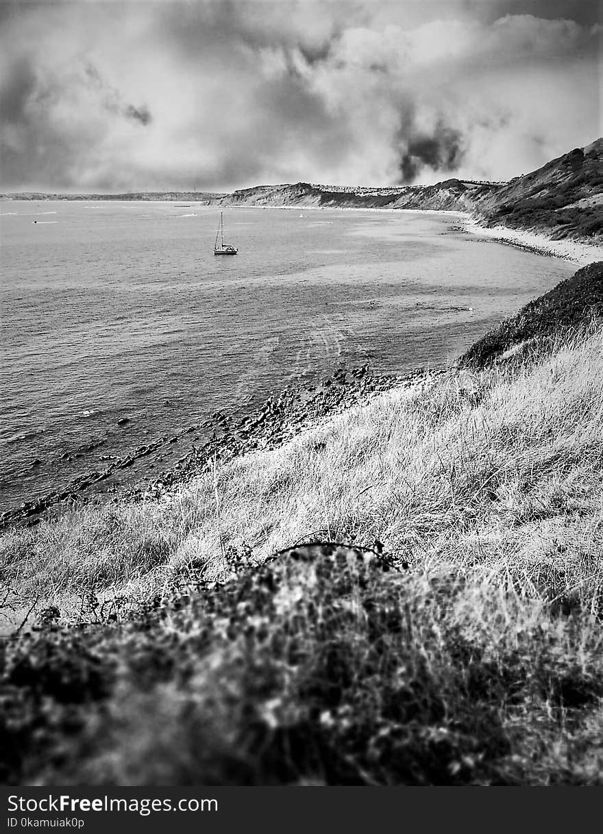 Grayscale Photography of Boat on Body of Water Near Mountain