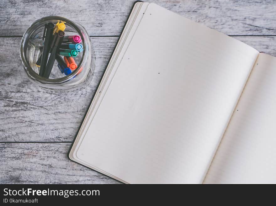 Photo of Blank Note Book Near Clear Jar