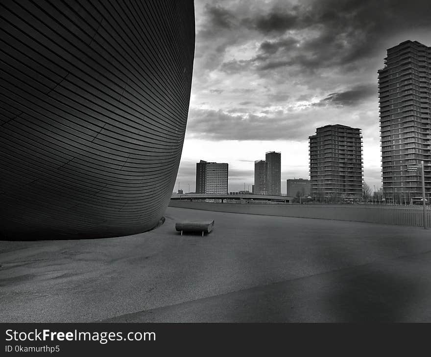 Greyscale Photo of Bench Beside Tall Building