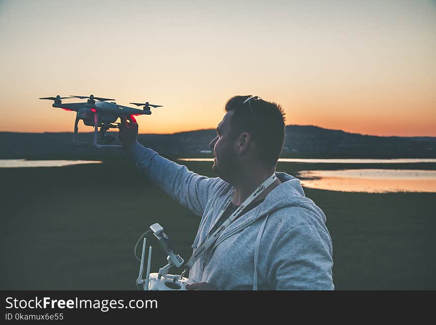 Man in Gray Jacket Holding Black Drone