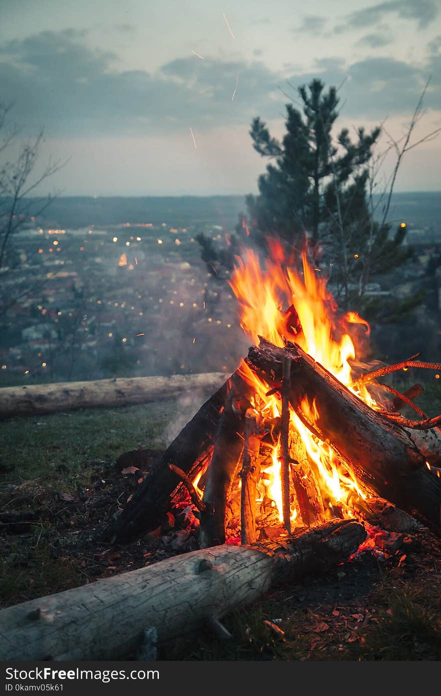 Photo of Bonfire Placed on High Ground in Front of City Under Cloudy Sky