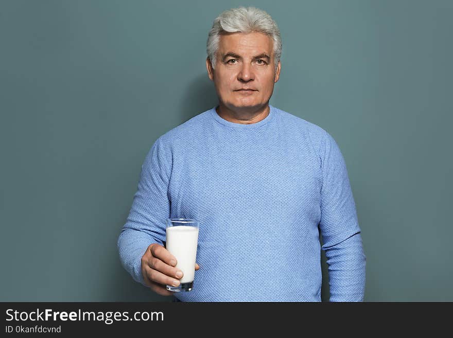 Mature man with dairy allergy holding glass of milk