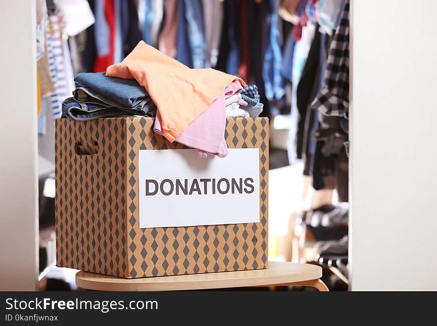 Donation box with clothes on table indoors