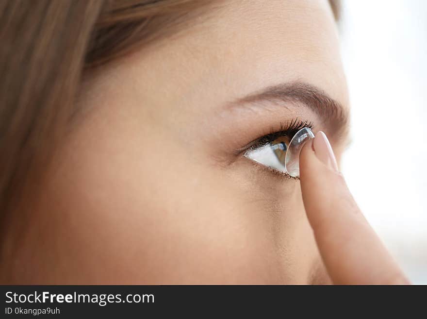 Young woman putting contact lens in her eye